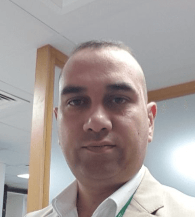 Man with short hair wearing a tan blazer and white shirt in an office.